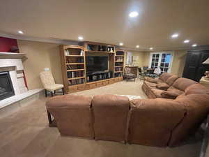 Carpeted living room featuring a glass covered fireplace, recessed lighting, and crown molding