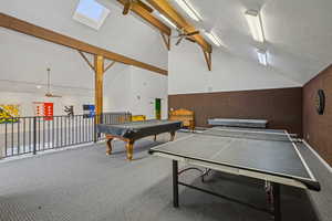 Recreation room with a ceiling fan, vaulted ceiling with skylight, a textured ceiling, billiards, and carpet flooring