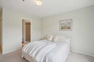 Bedroom featuring light carpet and baseboards