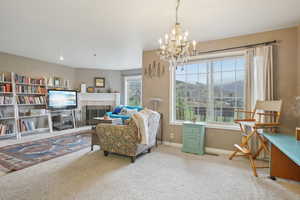 Sitting room featuring carpet floors, a tile fireplace, baseboards, and a notable chandelier