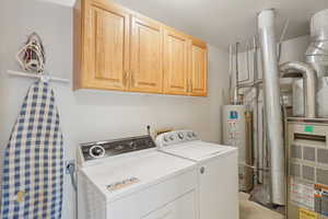 Washroom with separate washer and dryer, gas water heater, and cabinet space