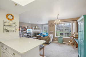 Kitchen with a tiled fireplace, baseboards, a kitchen bar, white cabinetry, and light colored carpet