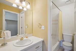 Full bathroom with tile patterned floors, visible vents, toilet, vanity, and shower / bath combo with shower curtain