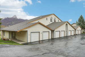 View of front facade with stucco siding, roof with shingles, and community garages