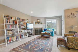 Living area featuring a tiled fireplace, baseboards, and carpet
