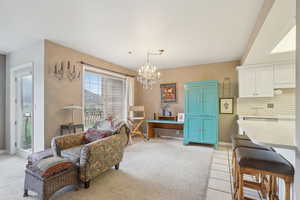 Sitting room featuring baseboards, a chandelier, and light colored carpet