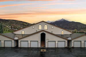View of front of house with community garages, stucco siding, and a mountain view