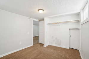 Unfurnished bedroom with a textured ceiling, a closet, carpet, baseboards, and visible vents