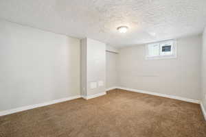 Basement featuring baseboards, carpet flooring, and a textured ceiling