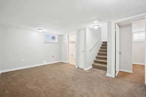 Below grade area featuring baseboards, stairs, and carpet