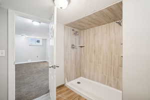 Bathroom with baseboards and a tile shower