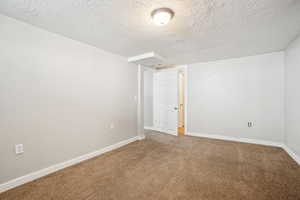 Carpeted spare room with a textured ceiling and baseboards