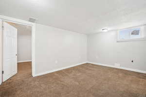 Below grade area featuring baseboards, visible vents, and carpet floors