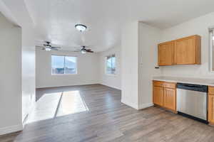 Kitchen with light wood-style flooring, light countertops, baseboards, a ceiling fan, and dishwasher