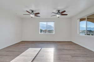 Family room with a wealth of natural light, a ceiling fan, wood finished floors, and baseboards