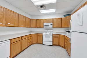 Clubhouse Kitchen with visible vents, a drop ceiling, white appliances, and light countertops