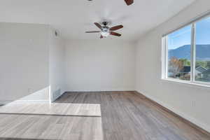 Family room featuring wood finished floors, visible vents, a ceiling fan, and baseboards