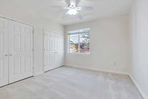 Master bedroom featuring baseboards, two closets, a ceiling fan, and light colored carpet