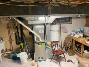 Utility room featuring strapped water heater