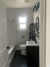 Full bath with tile patterned floors, a textured ceiling, toilet, shower / bathing tub combination, and vanity