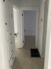 Hallway with light wood-type flooring and visible vents