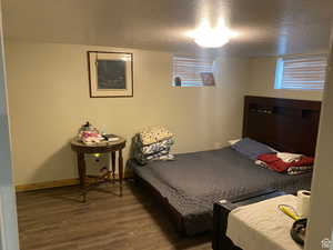 Bedroom featuring baseboards, wood finished floors, and a textured ceiling