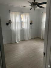 Empty room featuring light wood-style flooring, a ceiling fan, and baseboards