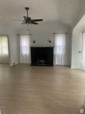 Unfurnished living room featuring light wood-style floors, vaulted ceiling, visible vents, and a ceiling fan