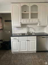 Kitchen with dark countertops, dishwasher, a sink, and backsplash