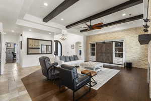Living room featuring arched walkways, beam ceiling, ceiling fan, and recessed lighting