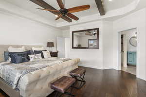 Bedroom featuring ceiling fan, beamed ceiling, a raised ceiling, dark wood finished floors, and baseboards