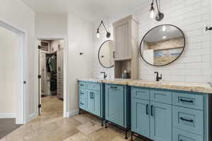 Full bathroom featuring two vanities, baseboards, and a sink