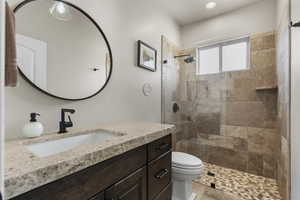 Full bathroom with a tile shower, recessed lighting, vanity, and toilet