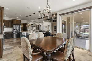 Dining room featuring stone tile flooring, arched walkways, a notable chandelier, and recessed lighting