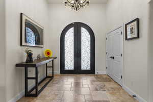 Entryway featuring stone tile floors, french doors, baseboards, and arched walkways