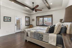 Bedroom with beamed ceiling, baseboards, dark wood-type flooring, visible vents, and access to exterior