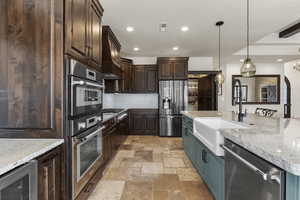 Kitchen with dark brown cabinetry, stone tile flooring, stainless steel appliances, backsplash, and wine cooler