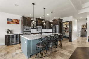Kitchen with dark brown cabinets, stone tile floors, appliances with stainless steel finishes, and wine cooler