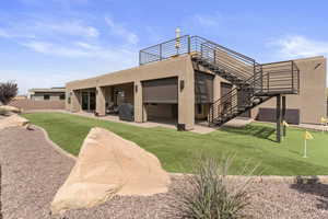 Rear view of house with stucco siding, a balcony, fence, and a patio