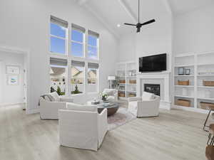 Great room with large windows w/power shades, vaulted ceiling, fan, gas log fireplace, and built-ins