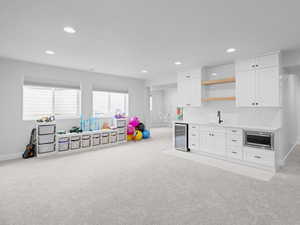 Rec room featuring a sink, light carpet, baseboards, beverage fridge, and recessed lighting