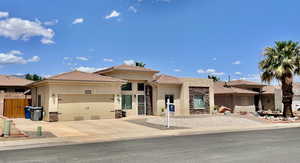 View of front of property with stone siding, stucco siding, an attached garage, and driveway
