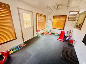 Rec room with rubber floors, rail lighting, baseboards, ceiling fan, and a textured ceiling