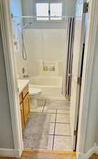 Bathroom with vanity, tile patterned floors, shower / tub combo, and toilet