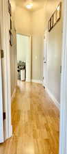Corridor with light wood-style flooring and baseboards