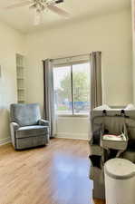 Sitting room with baseboards, light wood finished floors, and a ceiling fan