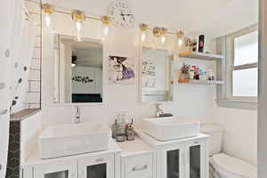 Bathroom with double vanity, toilet, and a sink