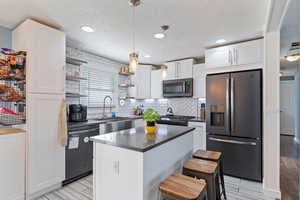 Kitchen with appliances with stainless steel finishes, open shelves, a sink, and white cabinetry