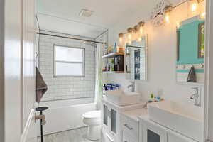 Full bathroom with shower / bath combo, visible vents, a sink, and toilet