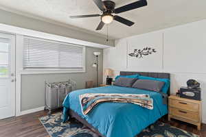 Bedroom with baseboards, a ceiling fan, wood finished floors, and a textured ceiling